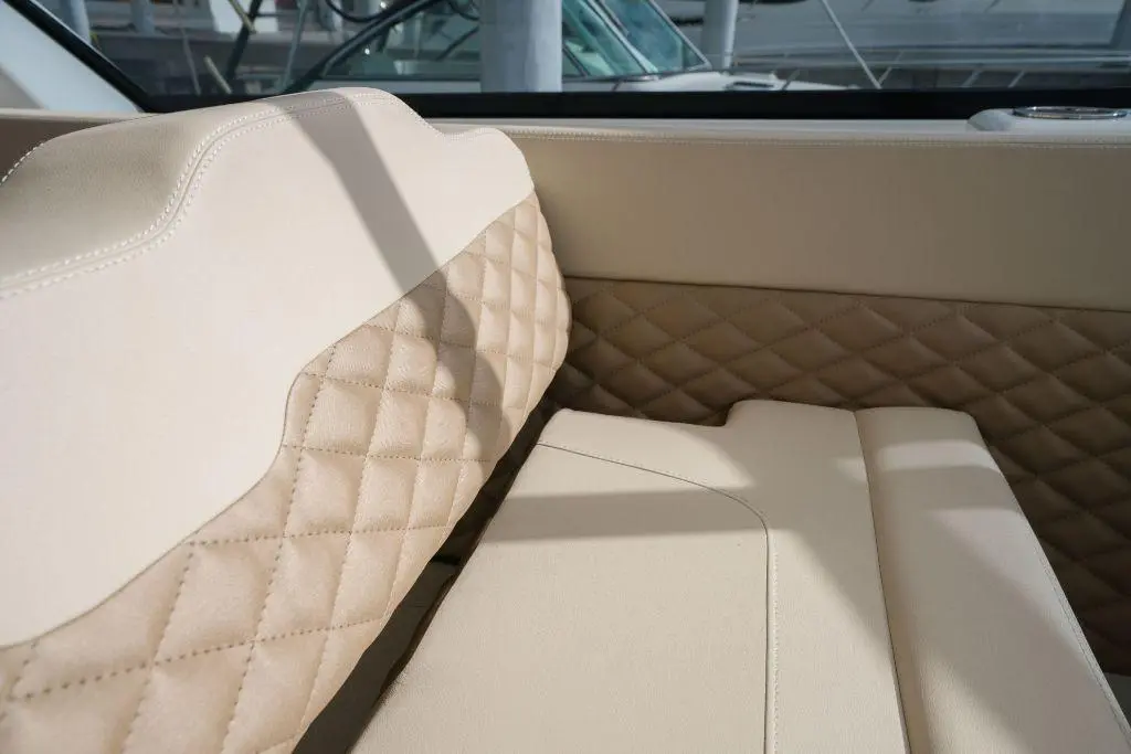 Luxurious boat seat with cream upholstery, featuring quilted texture and elegant design, set against a marina backdrop.